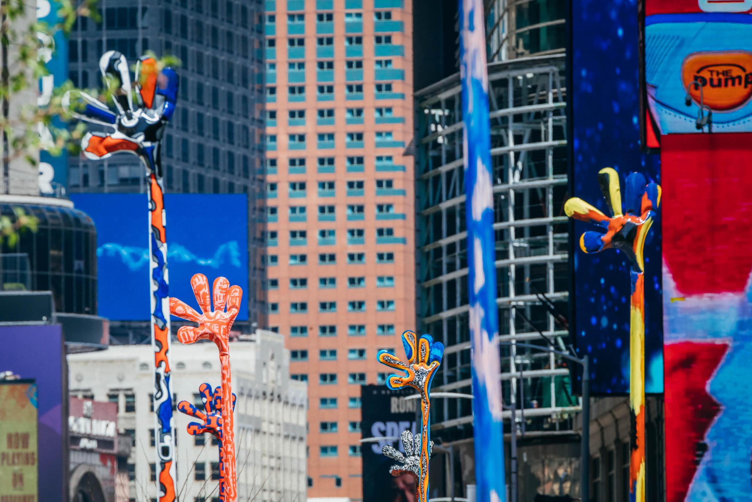 Colorful hands reaching into the air in front of buildings